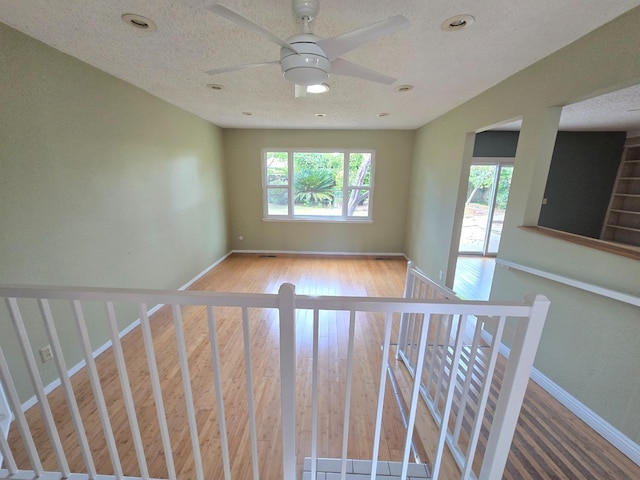 unfurnished room with baseboards, ceiling fan, wood finished floors, and a healthy amount of sunlight