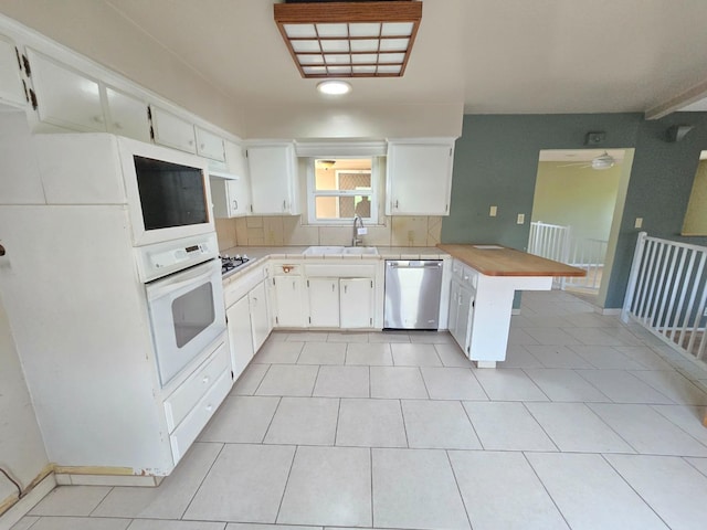 kitchen with stainless steel dishwasher, a sink, light countertops, a peninsula, and oven