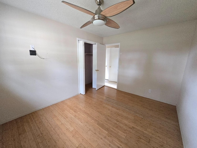 unfurnished bedroom with a closet, a ceiling fan, a textured ceiling, and wood finished floors