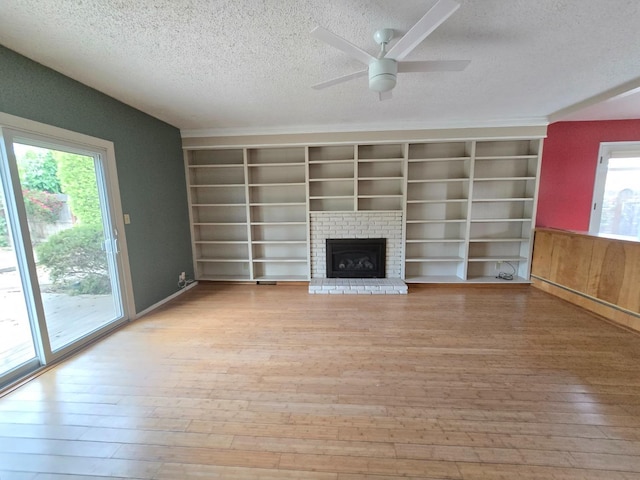 unfurnished living room with a fireplace, light wood-style flooring, a ceiling fan, and a textured ceiling