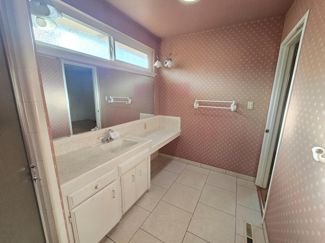 bathroom with tile patterned flooring, visible vents, vanity, baseboards, and walk in shower