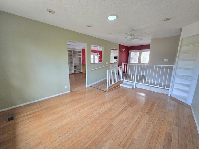 spare room featuring a textured ceiling, ceiling fan, baseboards, and light wood-style flooring