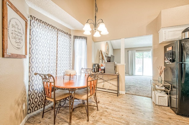dining room with an inviting chandelier, a textured wall, and light wood-type flooring