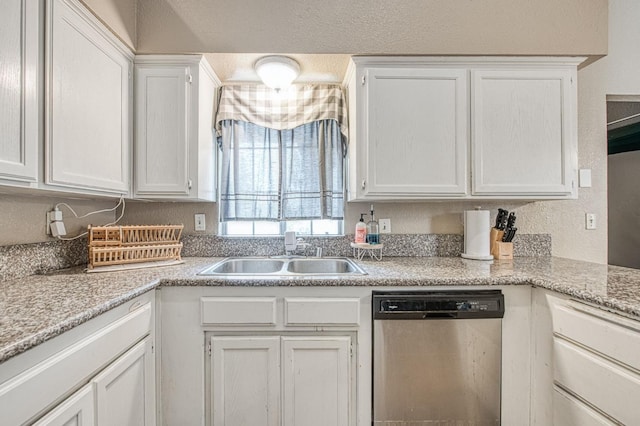 kitchen featuring stainless steel dishwasher, a sink, white cabinets, and light countertops