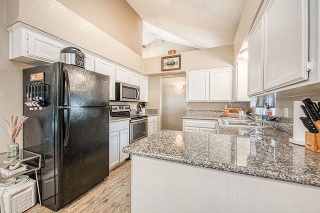 kitchen with appliances with stainless steel finishes, a sink, a peninsula, lofted ceiling, and white cabinetry