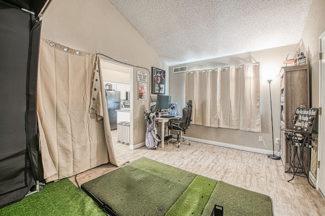 office space featuring visible vents, a textured ceiling, baseboards, wood finished floors, and vaulted ceiling