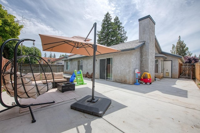 back of house featuring a patio, a fenced backyard, a chimney, a gate, and an outdoor fire pit