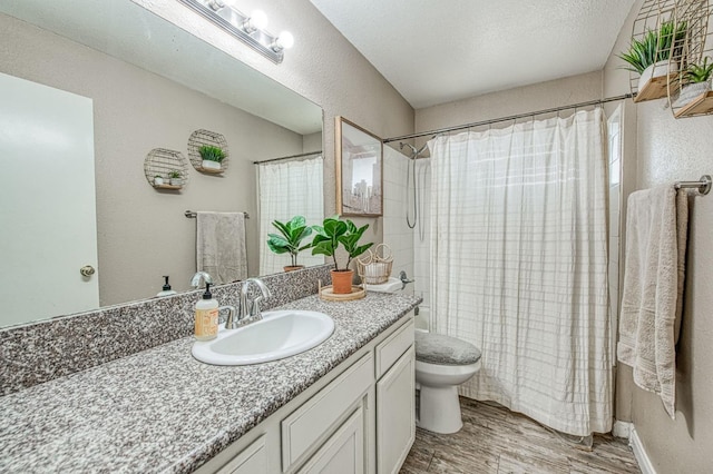 full bath with wood finished floors, vanity, toilet, a textured wall, and shower / bath combo with shower curtain