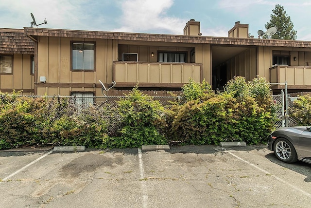 view of front of house with board and batten siding, a chimney, and uncovered parking