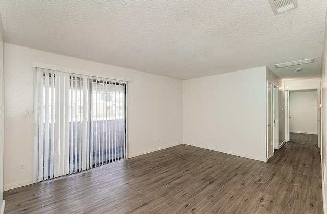 spare room with a textured ceiling, visible vents, and wood finished floors