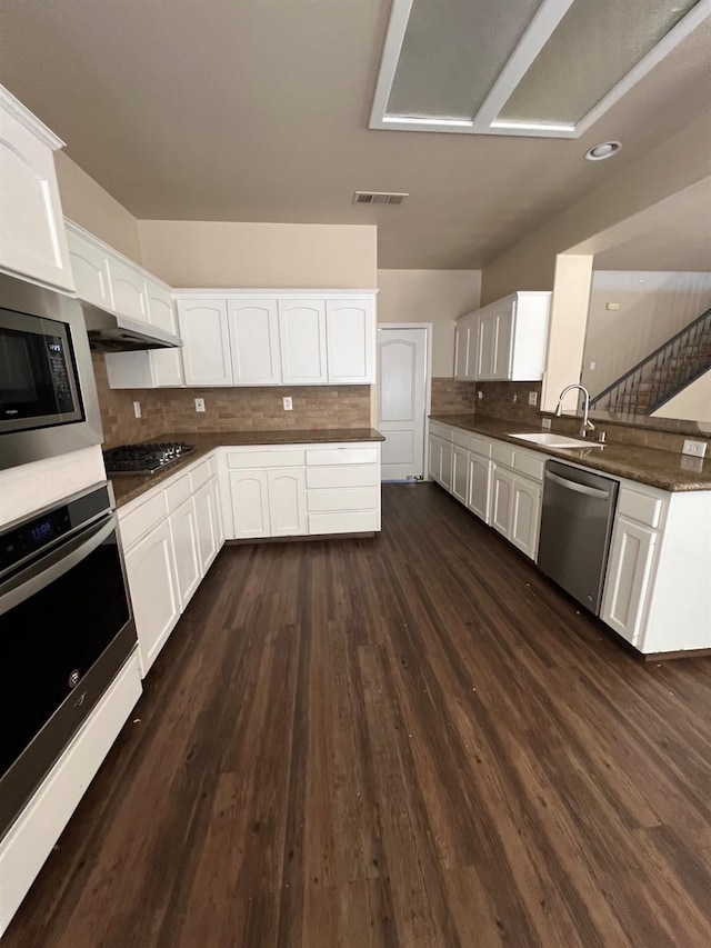 kitchen featuring a sink, decorative backsplash, appliances with stainless steel finishes, and white cabinetry