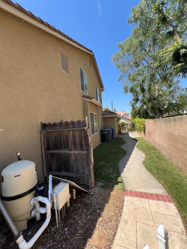 view of side of property featuring stucco siding, fence, and a patio