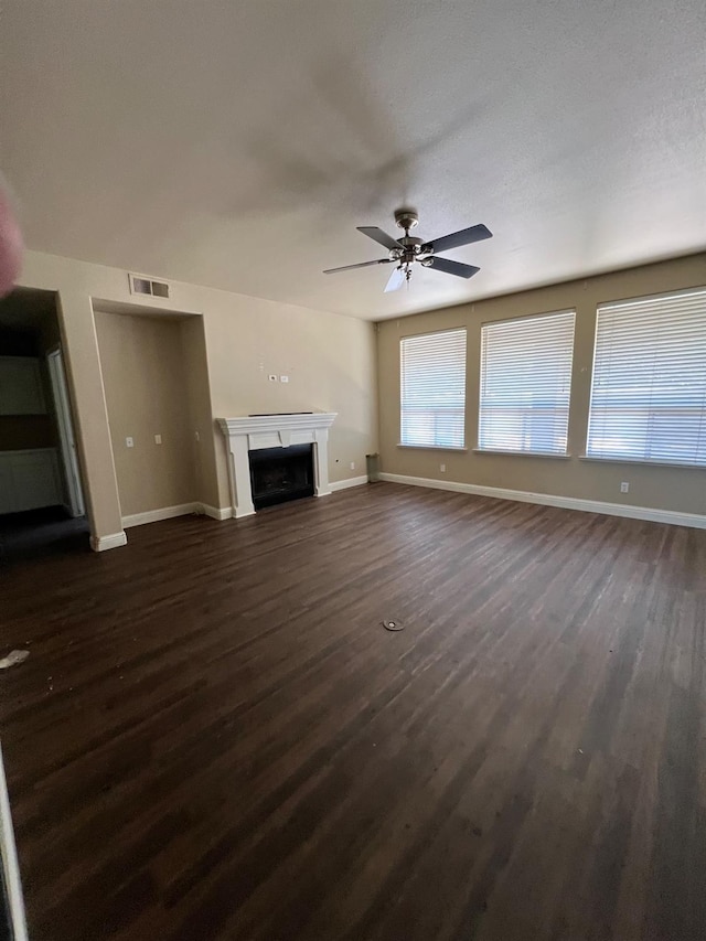 unfurnished living room featuring baseboards, a fireplace, dark wood finished floors, and visible vents