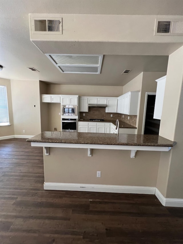 kitchen featuring a peninsula, baseboards, appliances with stainless steel finishes, and visible vents