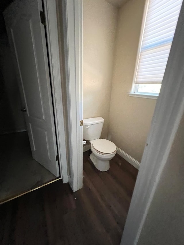 bathroom with baseboards, toilet, and wood finished floors