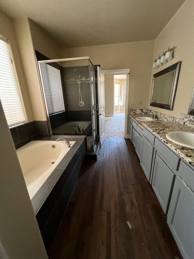 full bath featuring wood finished floors, a shower stall, a bath, and a wealth of natural light