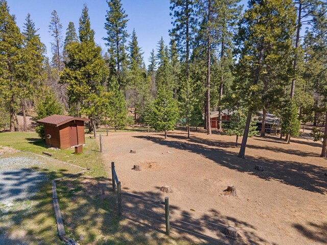 view of yard featuring fence, an outdoor structure, and a storage unit