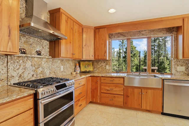 kitchen featuring wall chimney range hood, appliances with stainless steel finishes, tasteful backsplash, light stone countertops, and light tile patterned floors