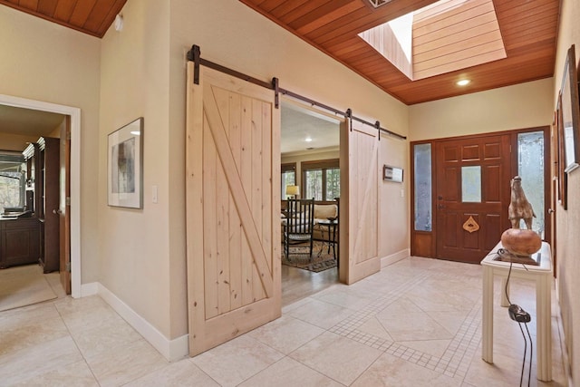 foyer featuring light tile patterned floors, wooden ceiling, baseboards, and a barn door