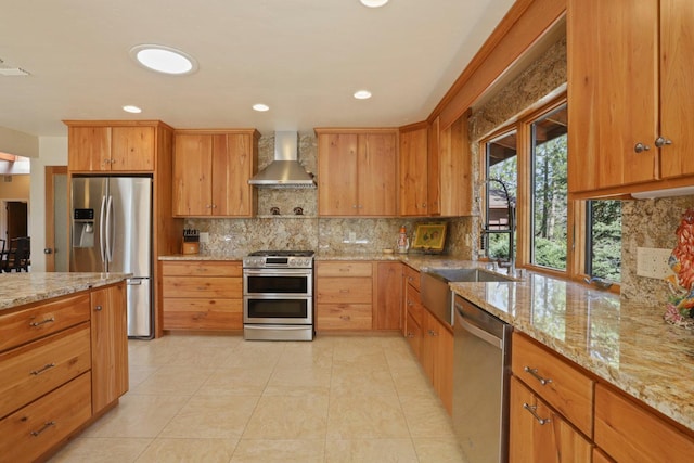 kitchen with light stone countertops, wall chimney range hood, recessed lighting, tasteful backsplash, and appliances with stainless steel finishes