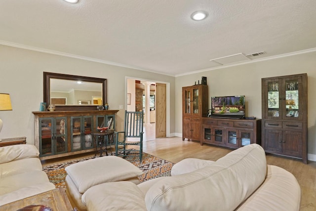 living area featuring ornamental molding, decorative columns, wood finished floors, and visible vents