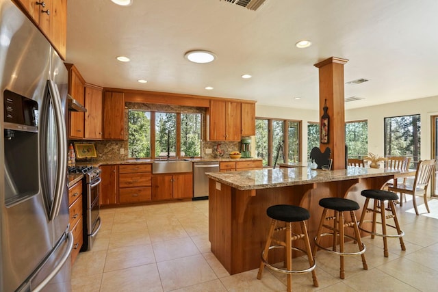 kitchen featuring plenty of natural light, brown cabinetry, stainless steel appliances, and tasteful backsplash