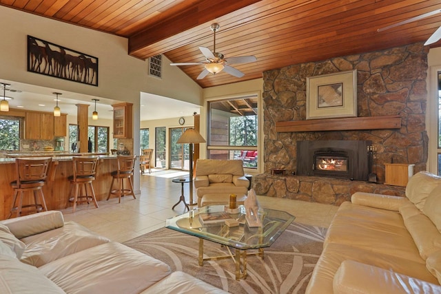 living area with light tile patterned flooring, ceiling fan, lofted ceiling with beams, a fireplace, and wooden ceiling