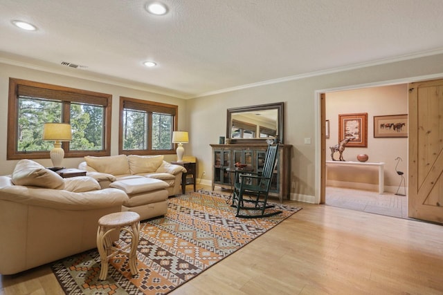 living area with baseboards, ornamental molding, wood finished floors, and visible vents