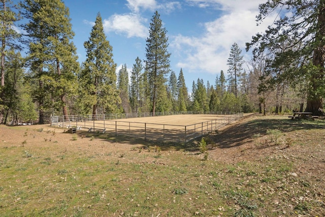view of yard with an enclosed area, fence, and a rural view