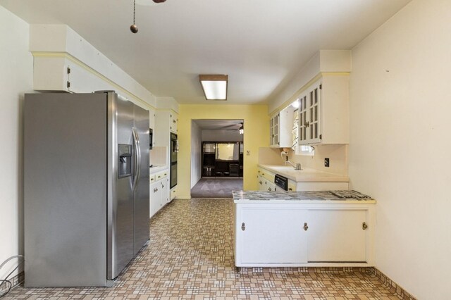kitchen featuring stainless steel fridge, light countertops, dobule oven black, a ceiling fan, and glass insert cabinets