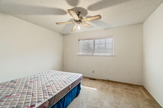 bedroom featuring a textured ceiling, carpet, a ceiling fan, baseboards, and visible vents
