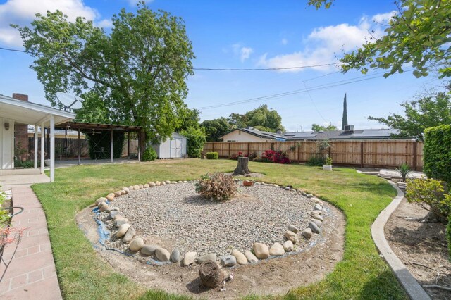 view of yard featuring an outdoor structure, a shed, a fenced backyard, and a patio area