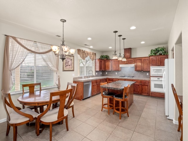9596 N Winery Ave, Fresno, CA 93720 - kitchen featuring white appliances, a chandelier, a center island, backsplash, and under cabinet range hood