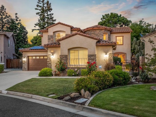 9596 N Winery Ave, Fresno, CA 93720 - mediterranean / spanish home featuring a front lawn, roof mounted solar panels, driveway, and stone siding