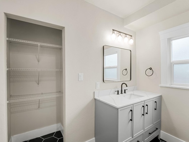 bathroom with baseboards, a spacious closet, and vanity