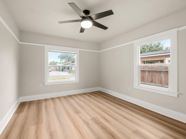 empty room with baseboards, ceiling fan, wood finished floors, and a healthy amount of sunlight