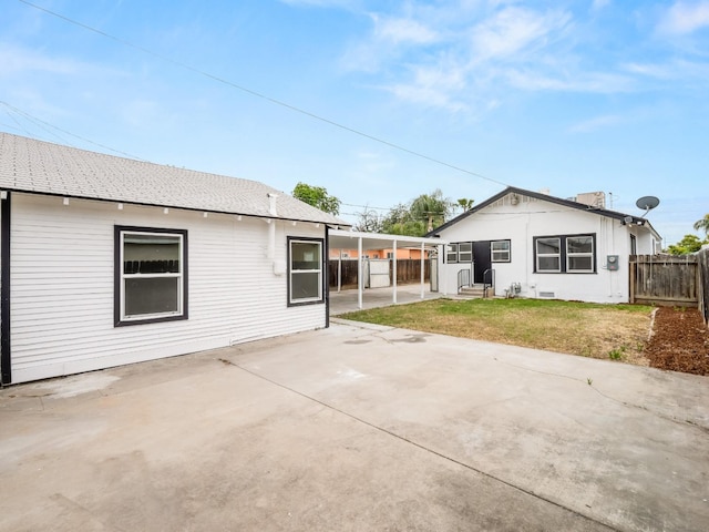 rear view of house featuring a lawn and fence