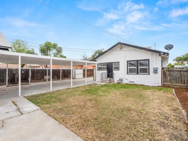rear view of property with stucco siding, fence, and a yard