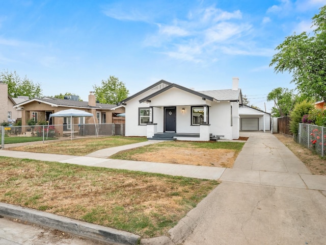 bungalow with a front lawn, fence, stucco siding, a chimney, and a detached garage