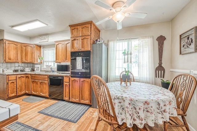 kitchen featuring brown cabinetry, tasteful backsplash, a ceiling fan, light wood finished floors, and black appliances