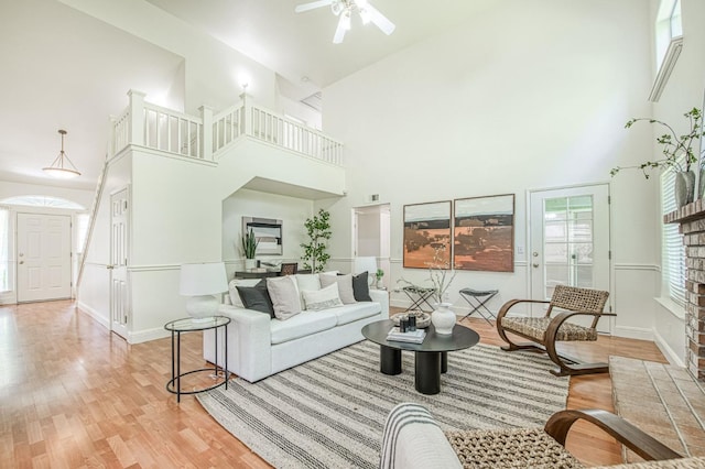 living area featuring wood finished floors, baseboards, a wealth of natural light, and a towering ceiling