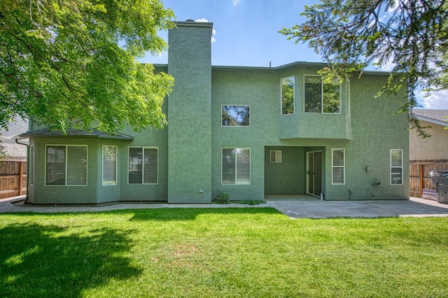 rear view of property with a patio area, stucco siding, a yard, and fence