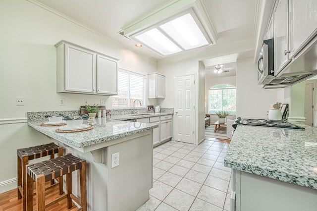 2072 E Lexington Ave, Fresno, CA 93720 - kitchen featuring a peninsula, a sink, a breakfast bar, light stone countertops, and ceiling fan