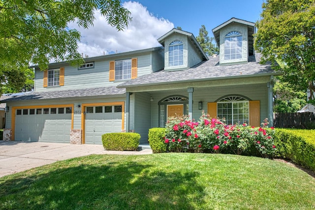 view of front of home featuring covered porch, driveway, fence, a front lawn, and an attached garage