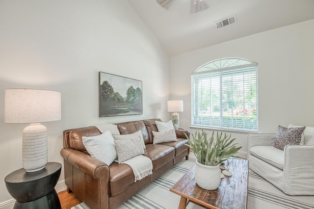 living area featuring a ceiling fan, baseboards, visible vents, and lofted ceiling