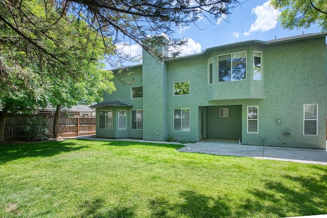 back of property featuring a patio area, stucco siding, a yard, and fence