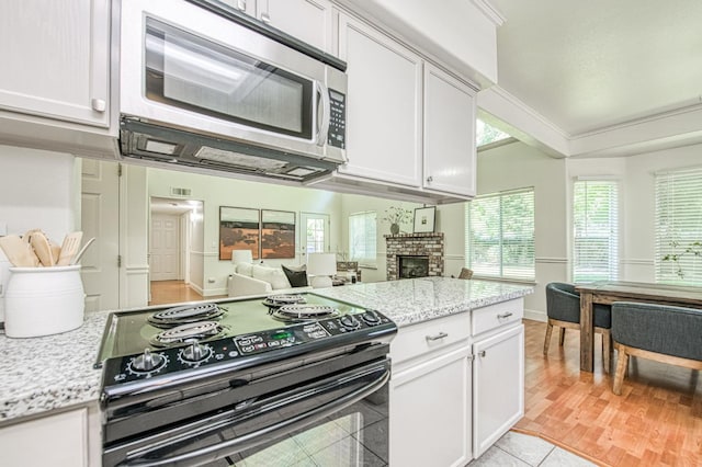 kitchen featuring a fireplace, open floor plan, white cabinetry, stainless steel microwave, and black range with electric stovetop