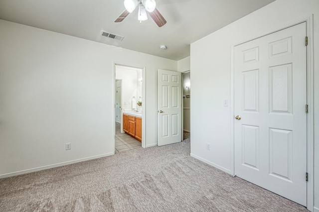 unfurnished bedroom featuring baseboards, ensuite bathroom, light carpet, and visible vents