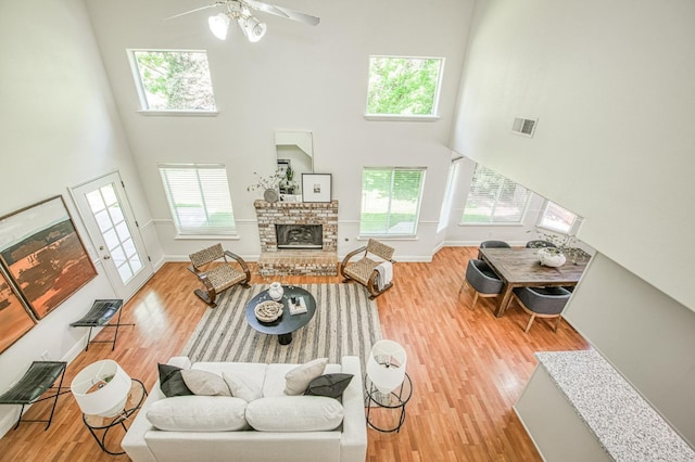 living area with a healthy amount of sunlight, visible vents, wood finished floors, and a towering ceiling