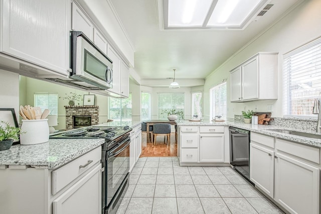 kitchen featuring crown molding, a sink, black appliances, a peninsula, and white cabinetry